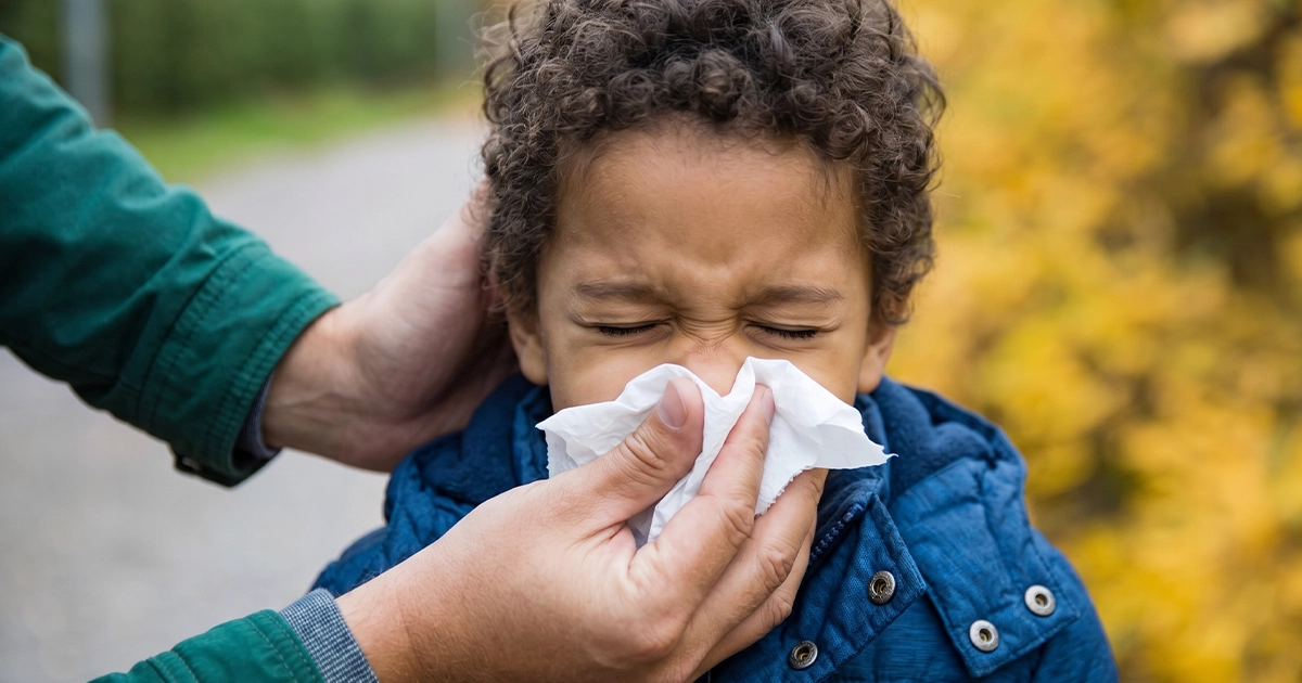 Adult wiping child's nose with a tissue