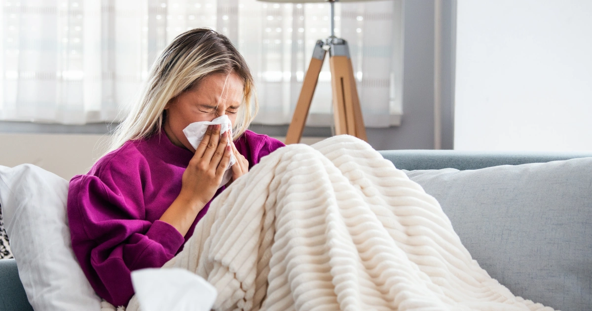 Woman with flu sneezing into tissue