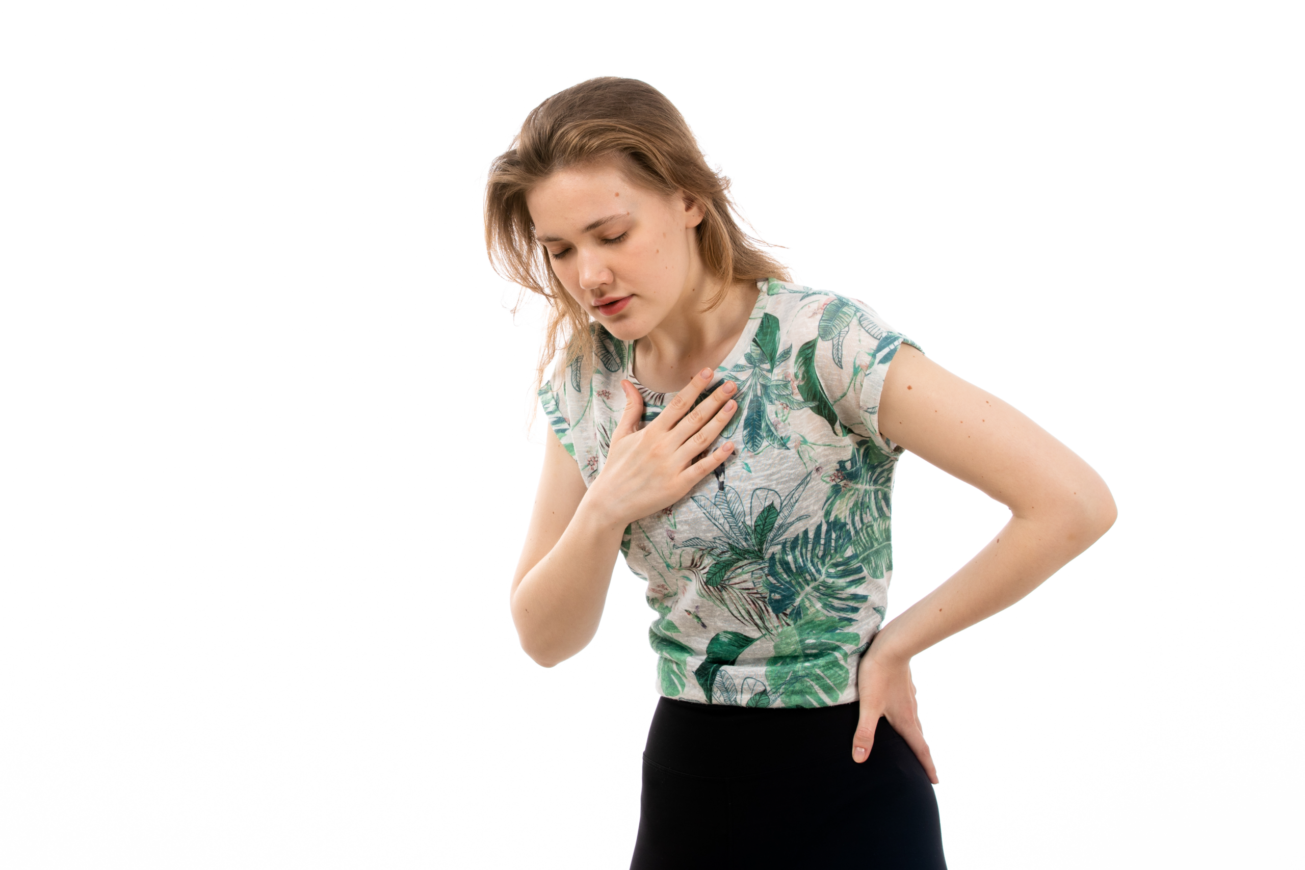 A young woman holding her hand to her chest with a pained expression against a white background.